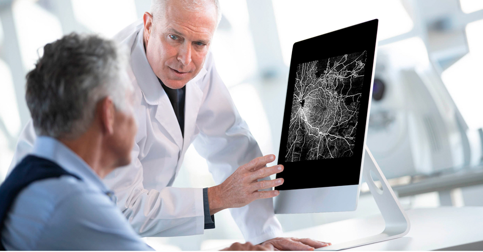 A doctor pointing to a screen of a medical view of the nerves of an eye to a patient.