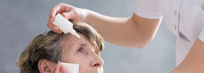 Nurse putting eye drops in eyes of an elderly patient